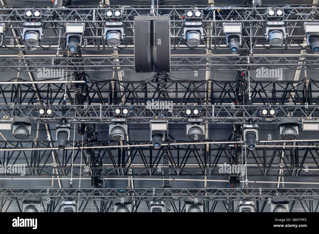 Close-up image of a professional concert stage rig with multiple spotlights, LED lights, moving head projectors, and hanging speakers. The photo captu Stock Photo