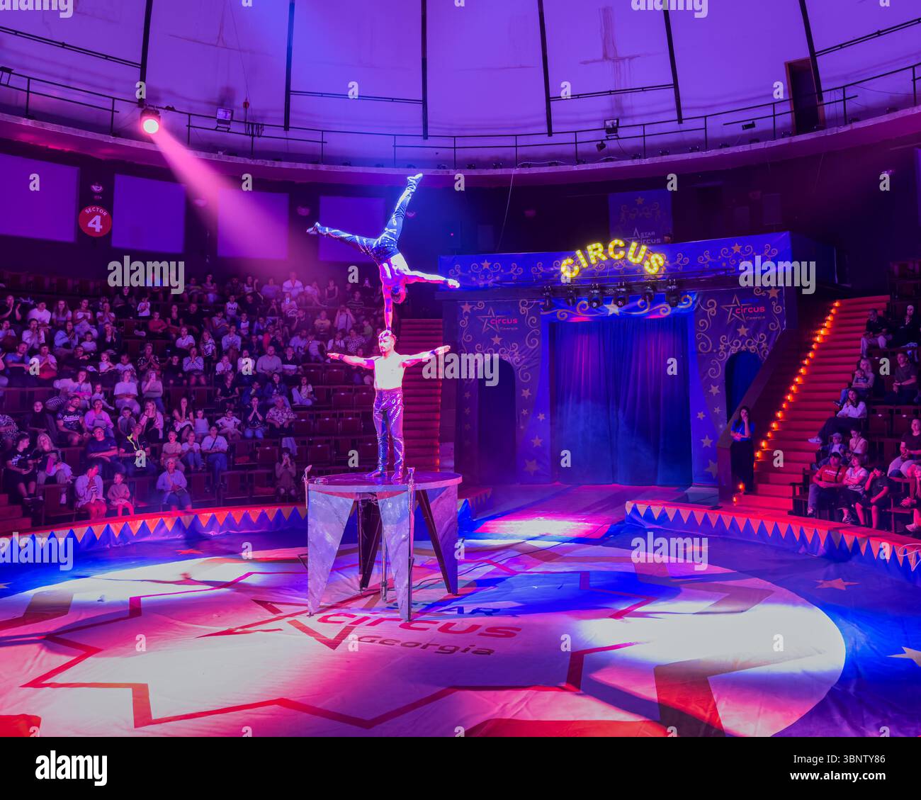 Partner acrobatics performance in a circus arena in Batumi, Georgia. Static hand-to-hand balance on platform. Editorial use only. Stock Photo