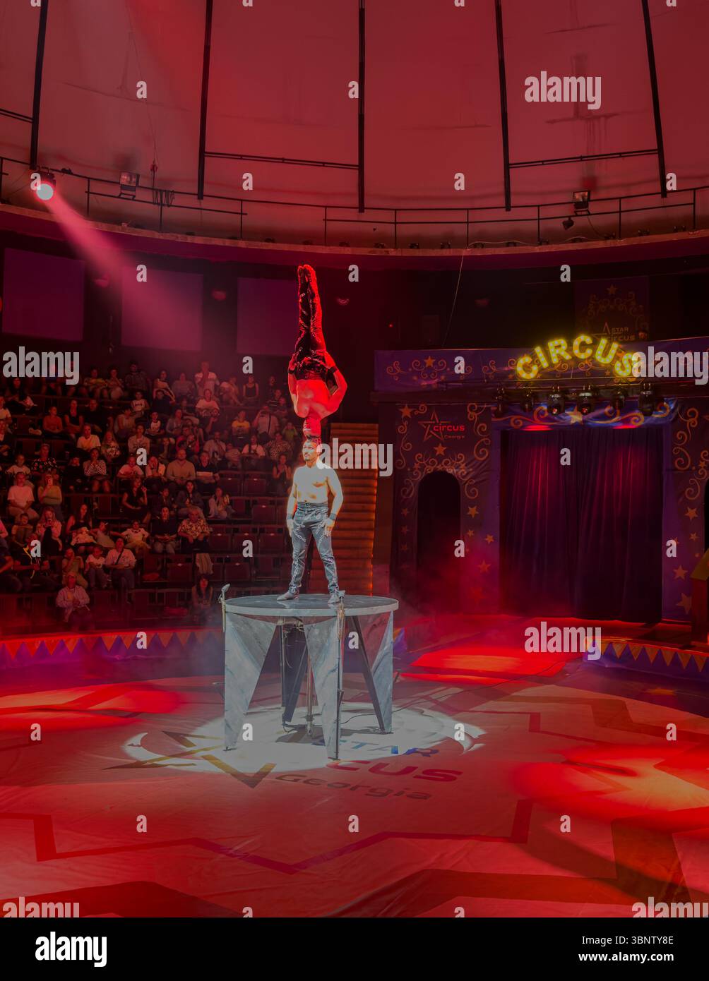 Acrobatic circus performance during live show in Batumi, Georgia. Two male artists on stage, one balancing upside down. Editorial use only. Stock Photo