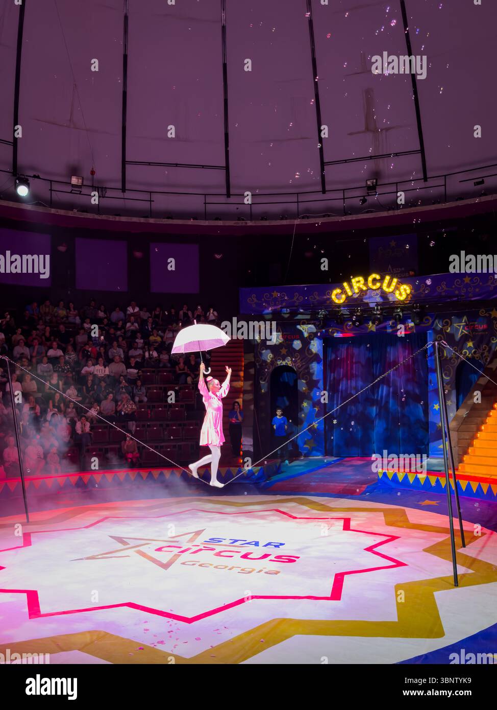 Tightrope walking act during a circus show in Batumi, Georgia. Performer in clown costume with umbrella. Editorial use only. Stock Photo