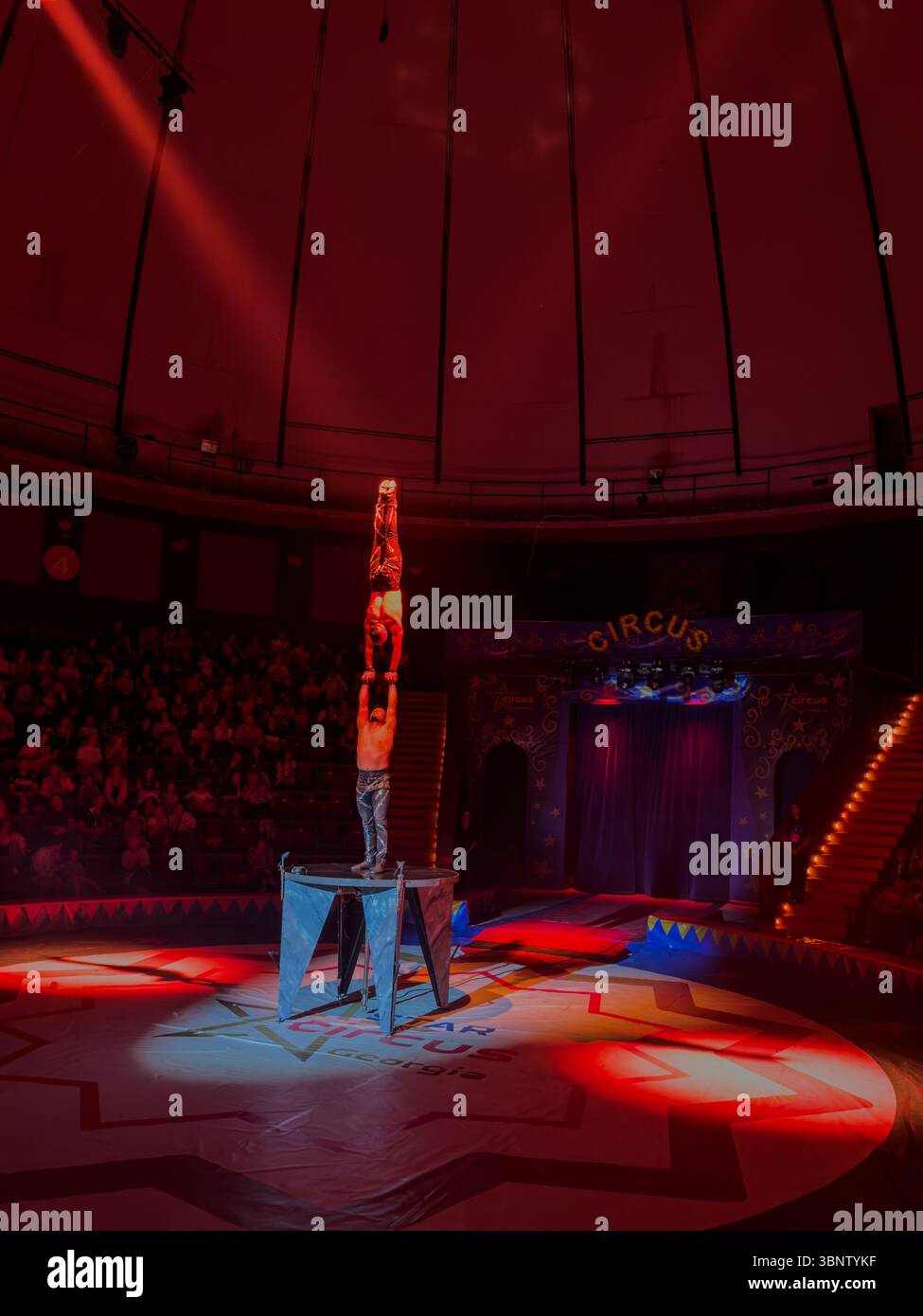 Circus performers executing a high hand-to-hand handstand on platform during a live show in Batumi, Georgia. Editorial use only. Stock Photo
