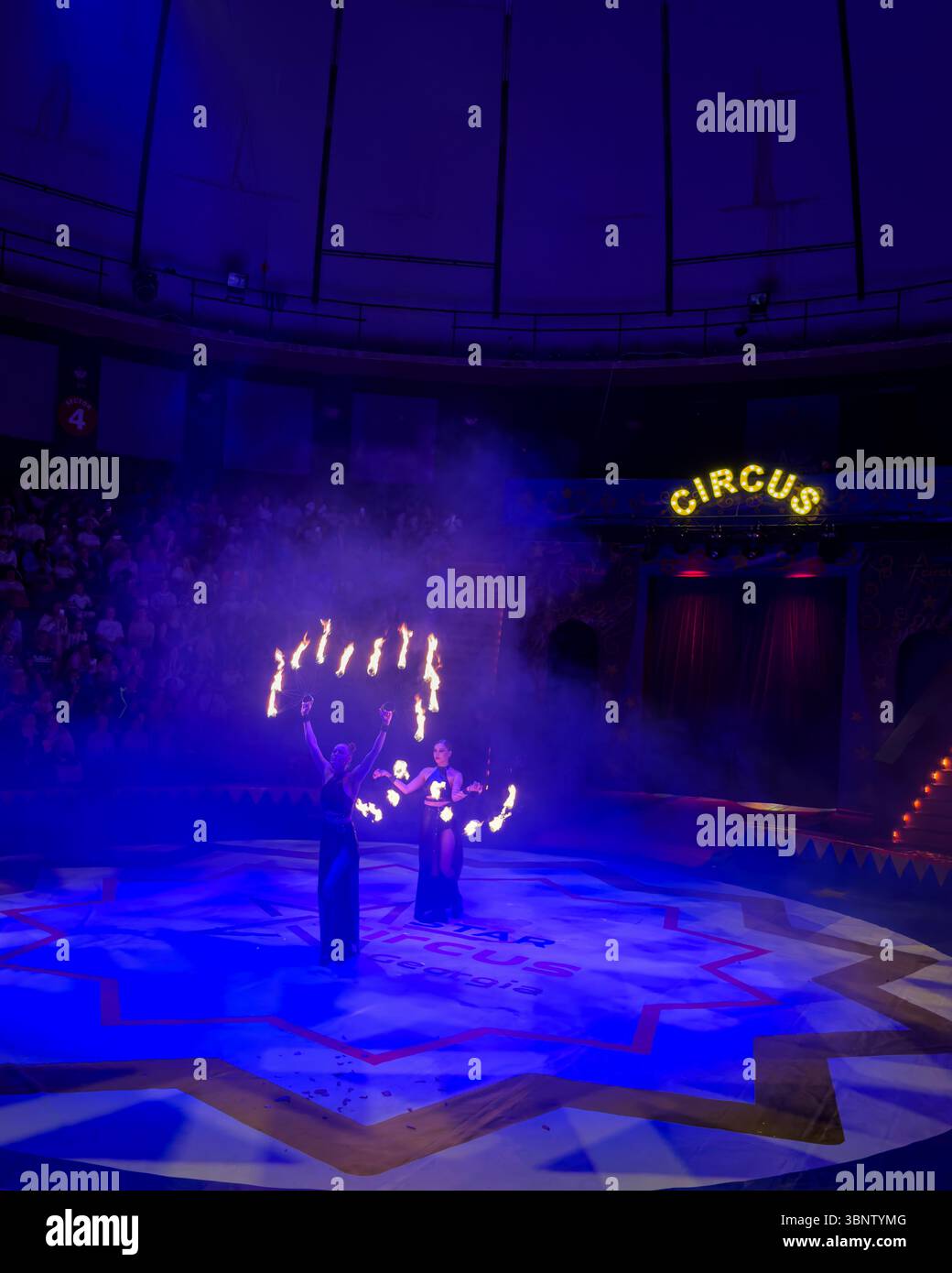 Fire poi performers on stage during a circus show in Batumi, Georgia. Dramatic lighting, smoke, and flame effects. Editorial use only. Stock Photo