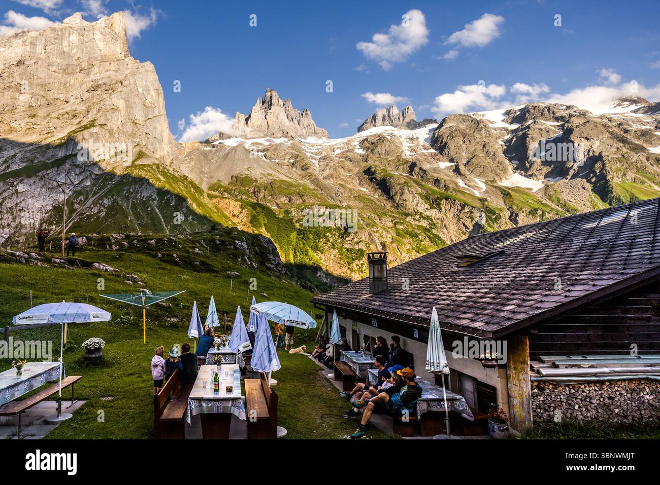 Guests at Hobiel Alp, all waiting for the sunset and the alpenglow at Großer Spannort. Evening ritual in the alpine landscape at the Hobiel-Alp, near Engelberg, Switzerland. The eldest family member performs the traditional call to prayer in front of all those present. This tradition shows the combination of deep piety and the impressive nature of the Swiss Alps. Hobiel, Engelberg, Uri, Switzerland Stock Photo