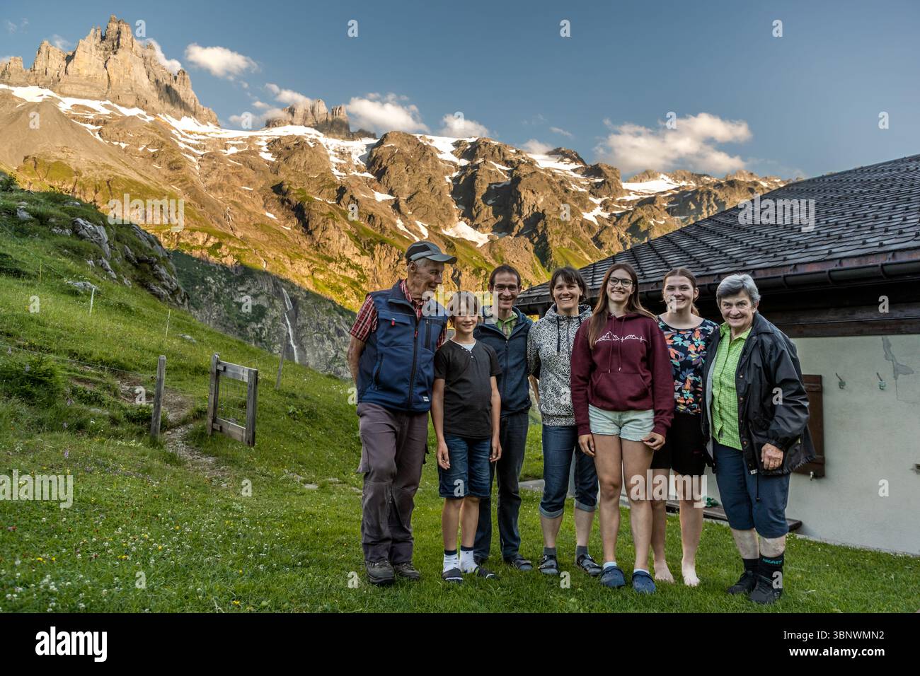 Three generations at Hobiel Alp: Sepp Zurflüh with his wife Theres, their son Ruedi with his wife Sibylle and their children. Three generations of a farming family pose on the Hobiel Alp, Engelberg, Uri, Switzerland, in front of the panorama of the Spannort Massif Stock Photo