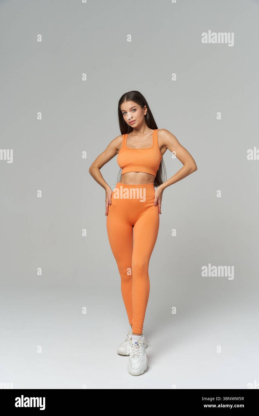 A slim and fit woman showcases her toned physique in a stylish orange ...