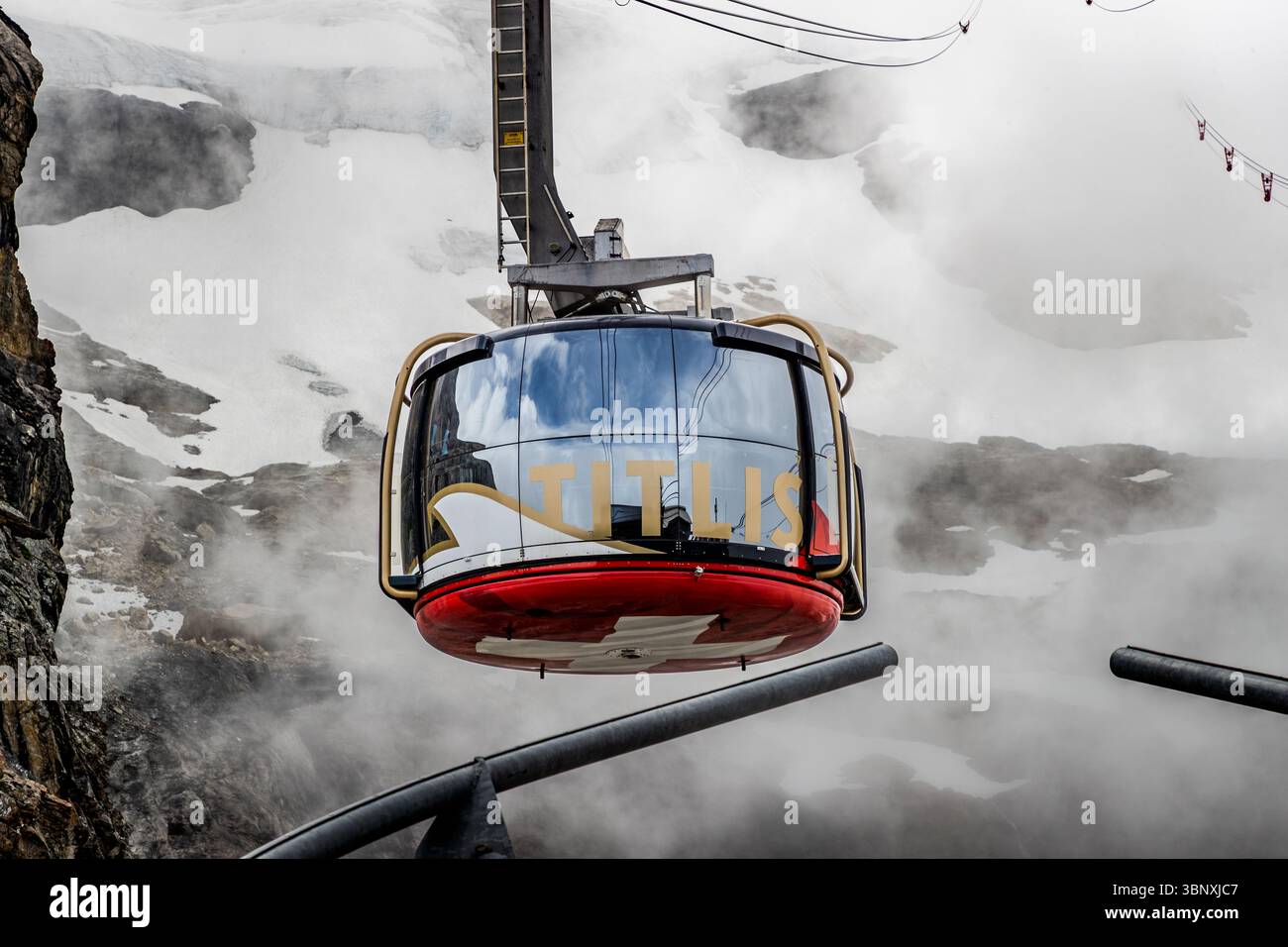 Visitors to Titlis Rotair can enjoy spectacular panoramic views. Once at the top, visitors can expect a major construction site until 2029. A gondola of the Titlis Rotair cable car, recognisable by the lettering 'TITLIS', transports visitors through the misty, snow-covered mountain landscape to the summit of the Titlis Stock Photo