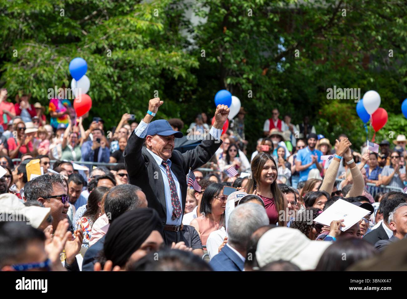 Seattle, Washington, USA. 4th July, 2025. Immigrants cheer enthusiastically as their home countries are named during a naturalization ceremony at Fisher Pavilion. The Honorable David G. Estudillo, Chief United States District Judge for the Western District Court of Washington, swore in 501 applicants from 79 countries as new citizens at Seattle Center’s 40th Annual Naturalization Ceremony. Credit: Paul Christian Gordon/Alamy Live News Stock Photo