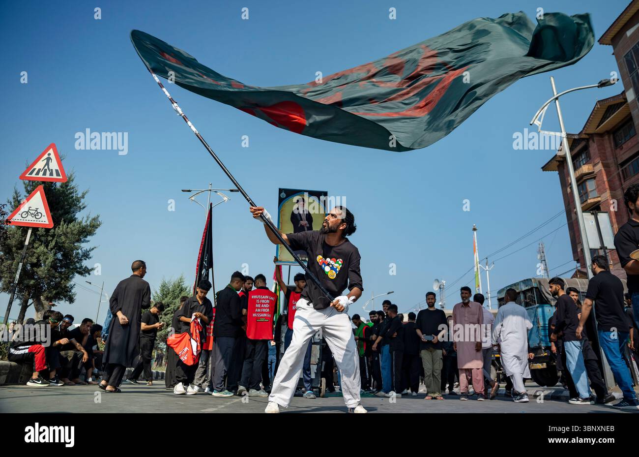 A Kashmiri Shia Muslim man waves a religious flag during a Muharram ...