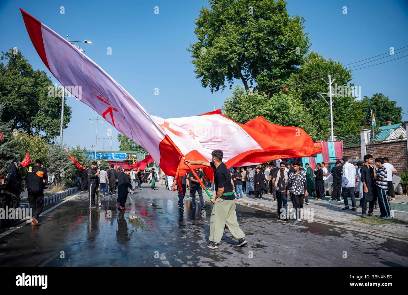 A Kashmiri Shia Muslim man waves a religious flag during a Muharram ...