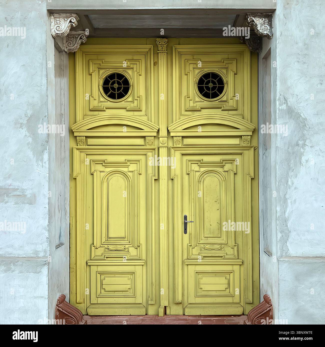 An ornate yellow double door in Warsaw, Poland, features intricate woodwork and circular glass insets, framed by sculpted classical corbels and faded - Smartphone Captured Stock Image