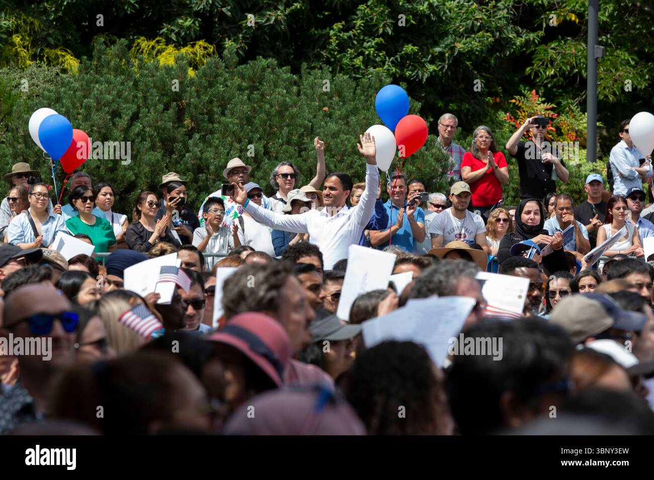 Seattle, Washington, USA. 4th July 2025. Immigrants cheer enthusiastically as their home countries are named during a naturalization ceremony at Fisher Pavilion. The Honorable David G. Estudillo, Chief United States District Judge for the Western District Court of Washington, swore in 501 applicants from 79 countries as new citizens at Seattle Center’s 40th Annual Naturalization Ceremony. Credit: Paul Christian Gordon/Alamy Live News Stock Photo