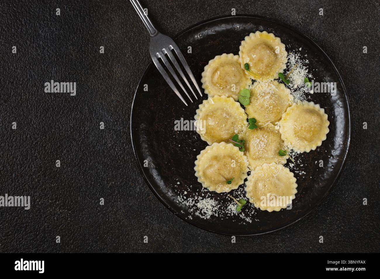 Fresh ravioli with cheese and microgreens, on a black plate, top view ...