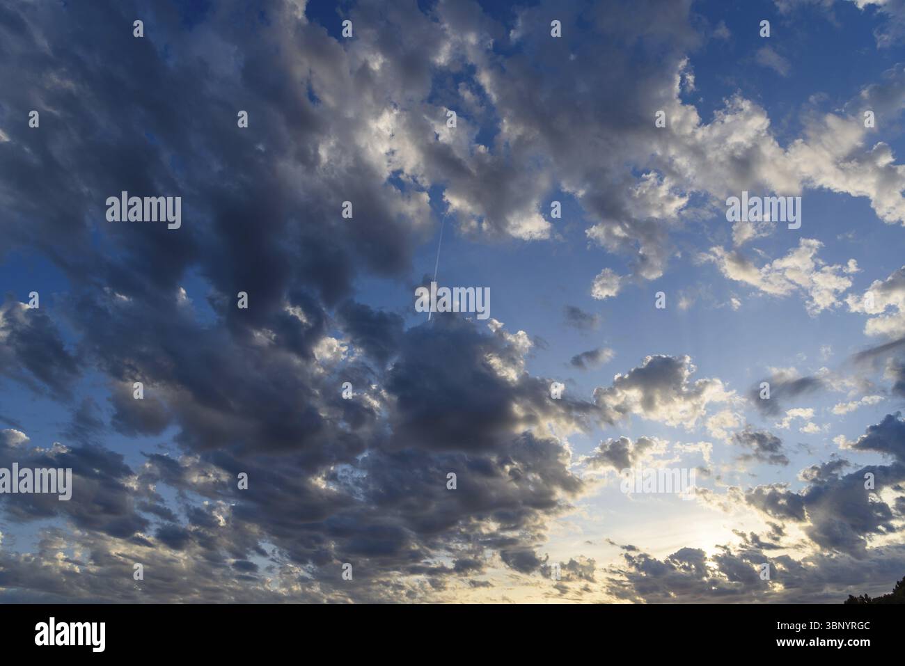 Beautiful white puffy clouds against blue sky during dramatic sunset Stock Photo