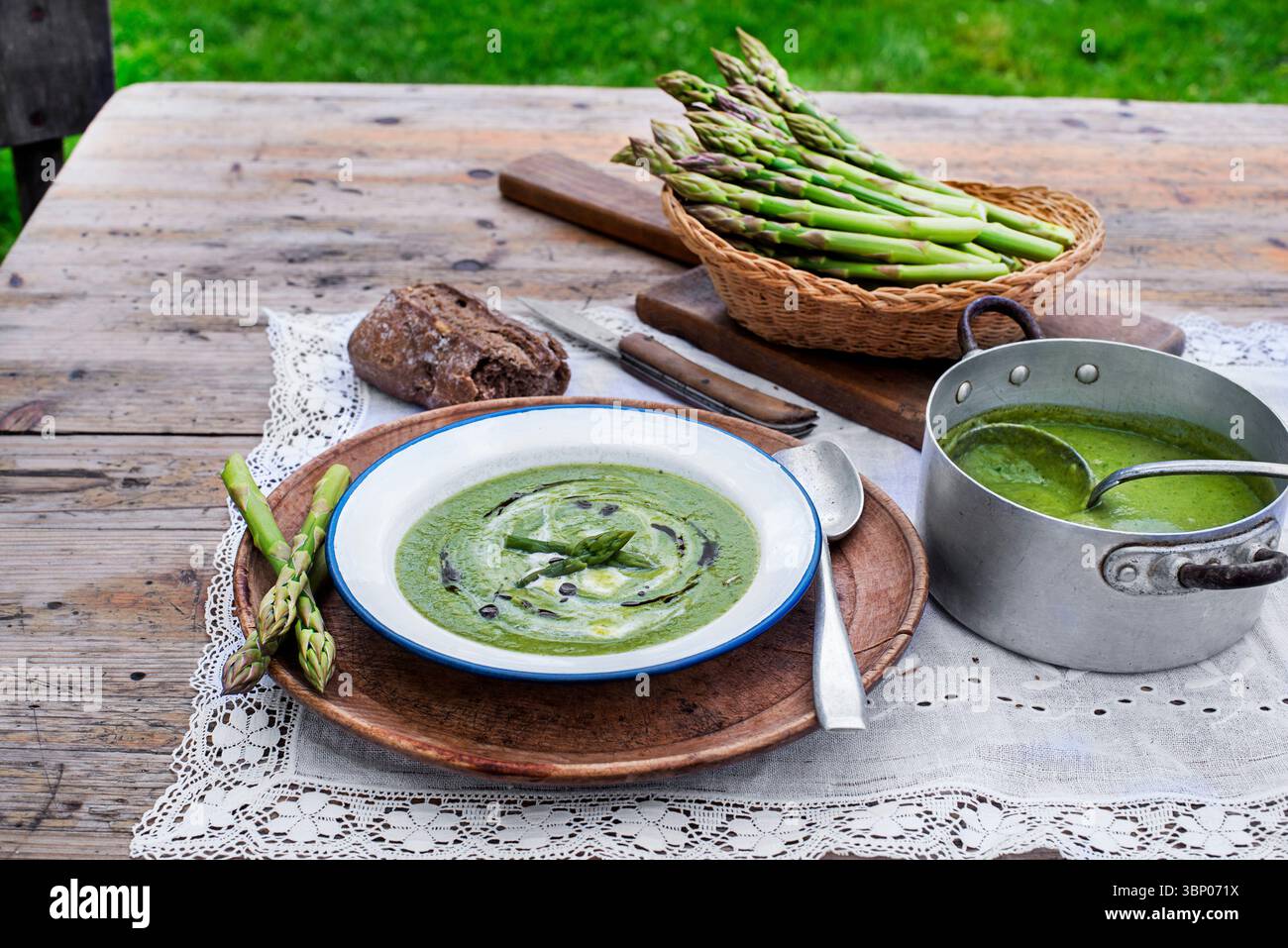 Fresh Asparagus creamy soup on wooden table outside in the garden Stock Photo