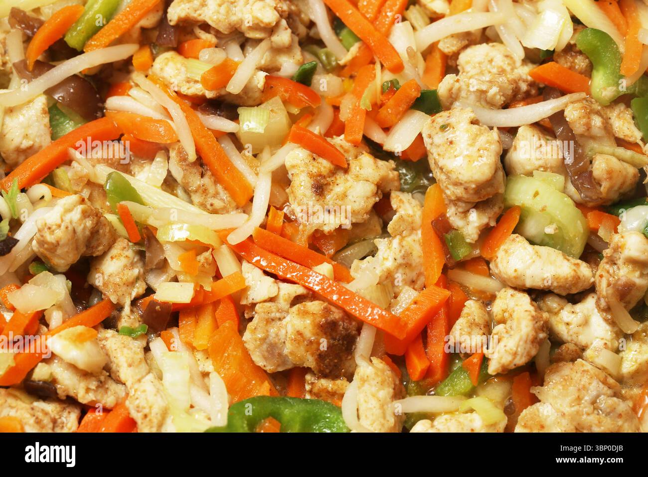 Closeup of stir fry dish with vegetables and tofu. Asian style vegan meal. Healthy colorful lunch with carrots, noodles, cabbage, and soy protein. Stock Photo