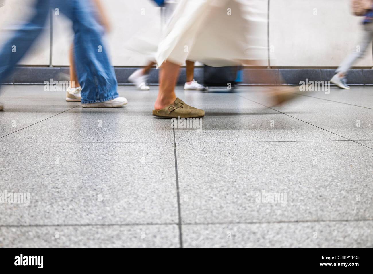 Motion blur of anonymous commuters walking indoors on polished urban floor during rush hour Stock Photo
