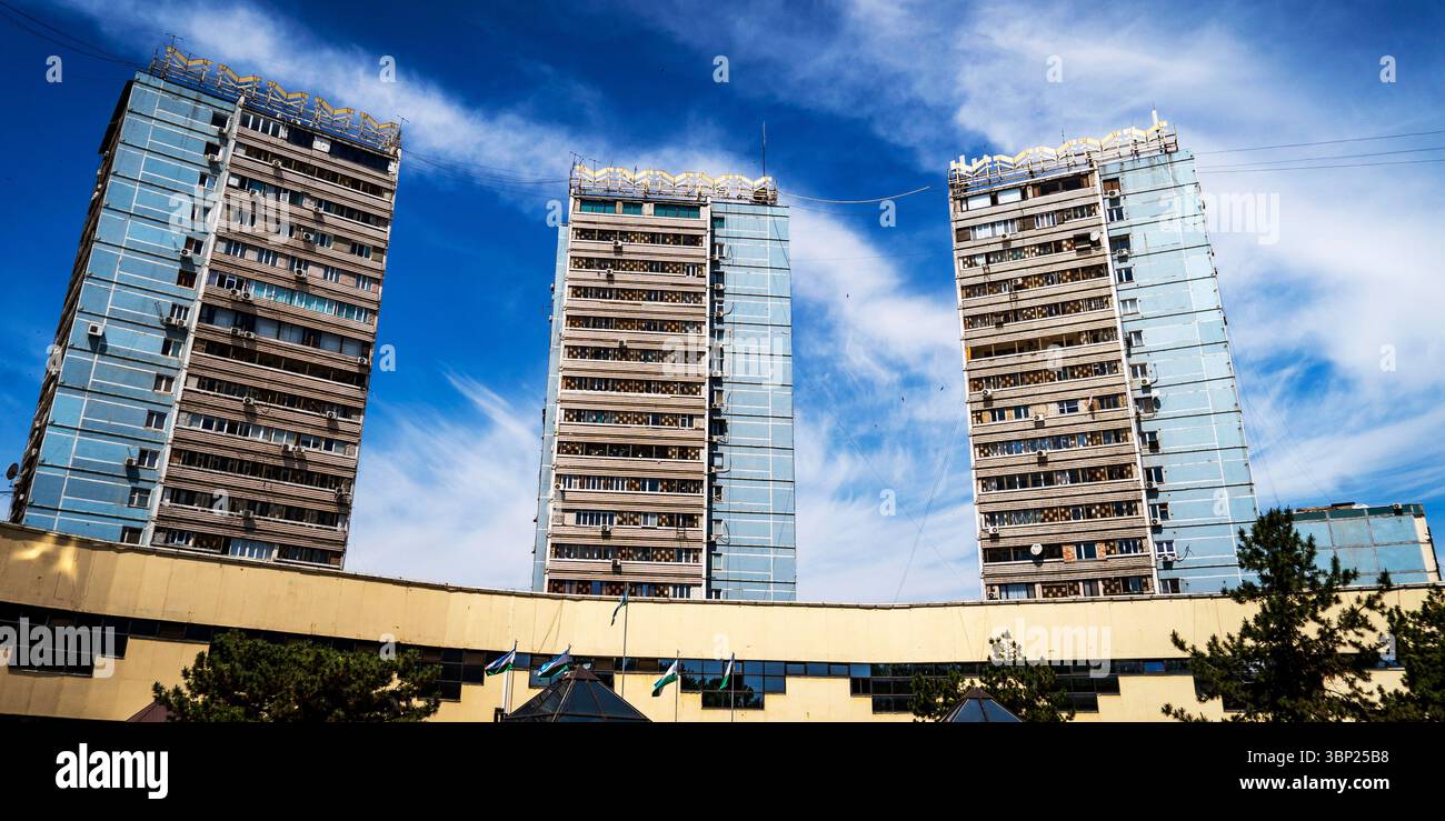Three modern high-rise buildings with glass facades against a blue sky ...