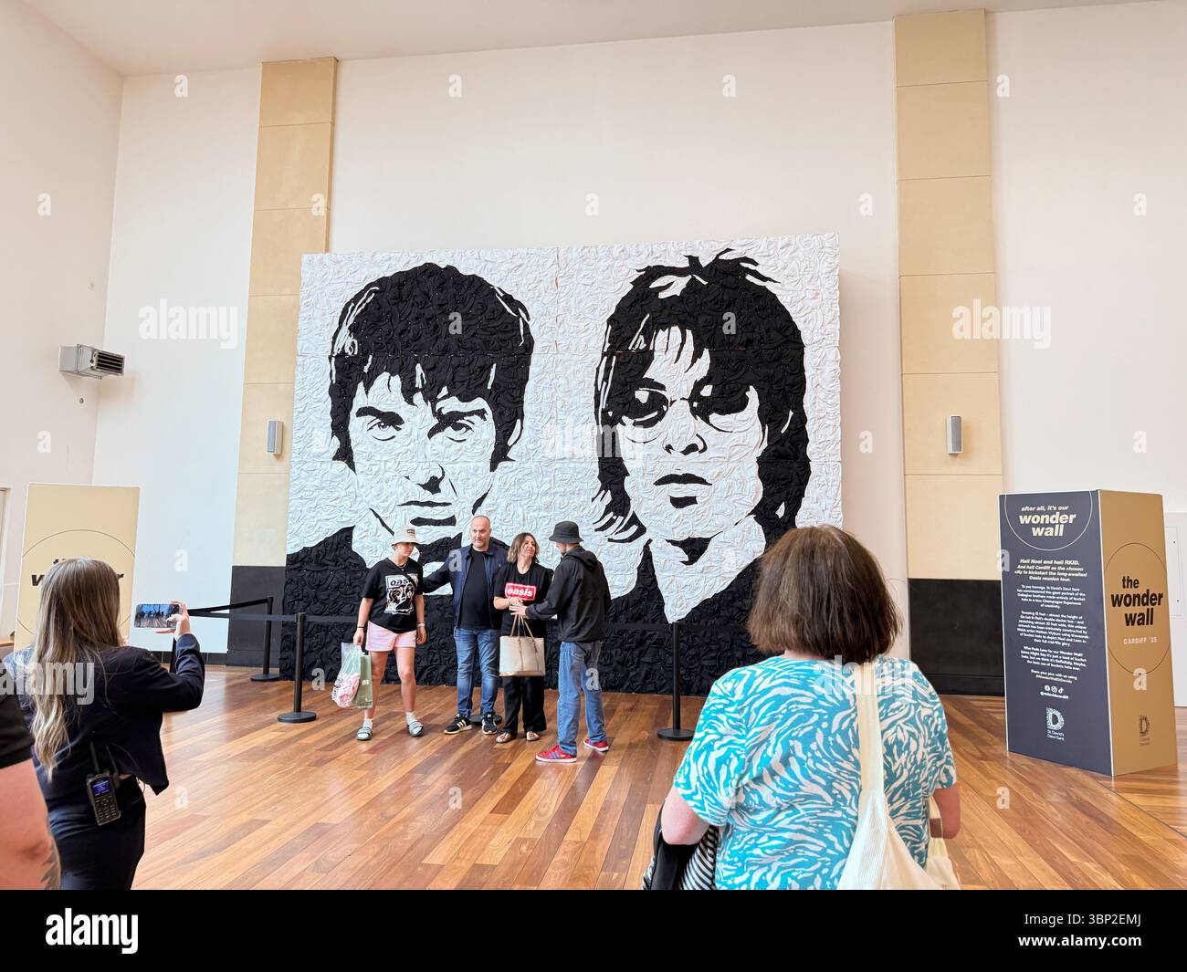 Oasis Fans Posing for Group Photo at Wonder Wall Display, St David’s 2 Shopping Centre Cardiff on the Oasis Live '25 tour, Wales - Smartphone Captured Stock Image