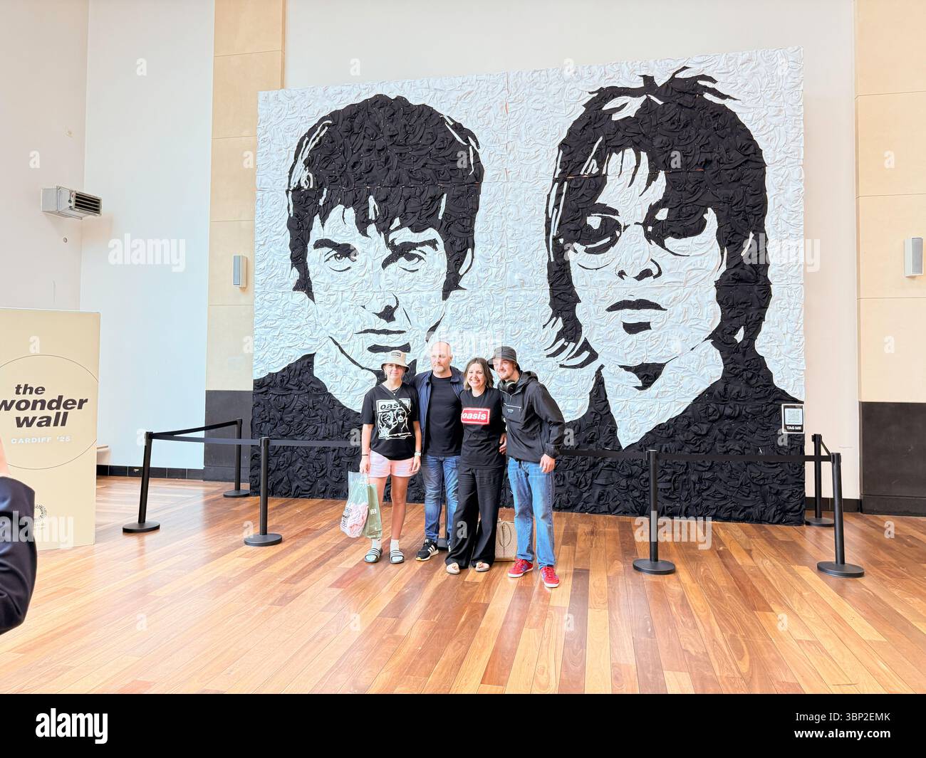 Oasis Fans Posing for Group Photo at Wonder Wall Display, St David’s 2 Shopping Centre Cardiff on the Oasis Live '25 tour, Wales - Smartphone Captured Stock Image
