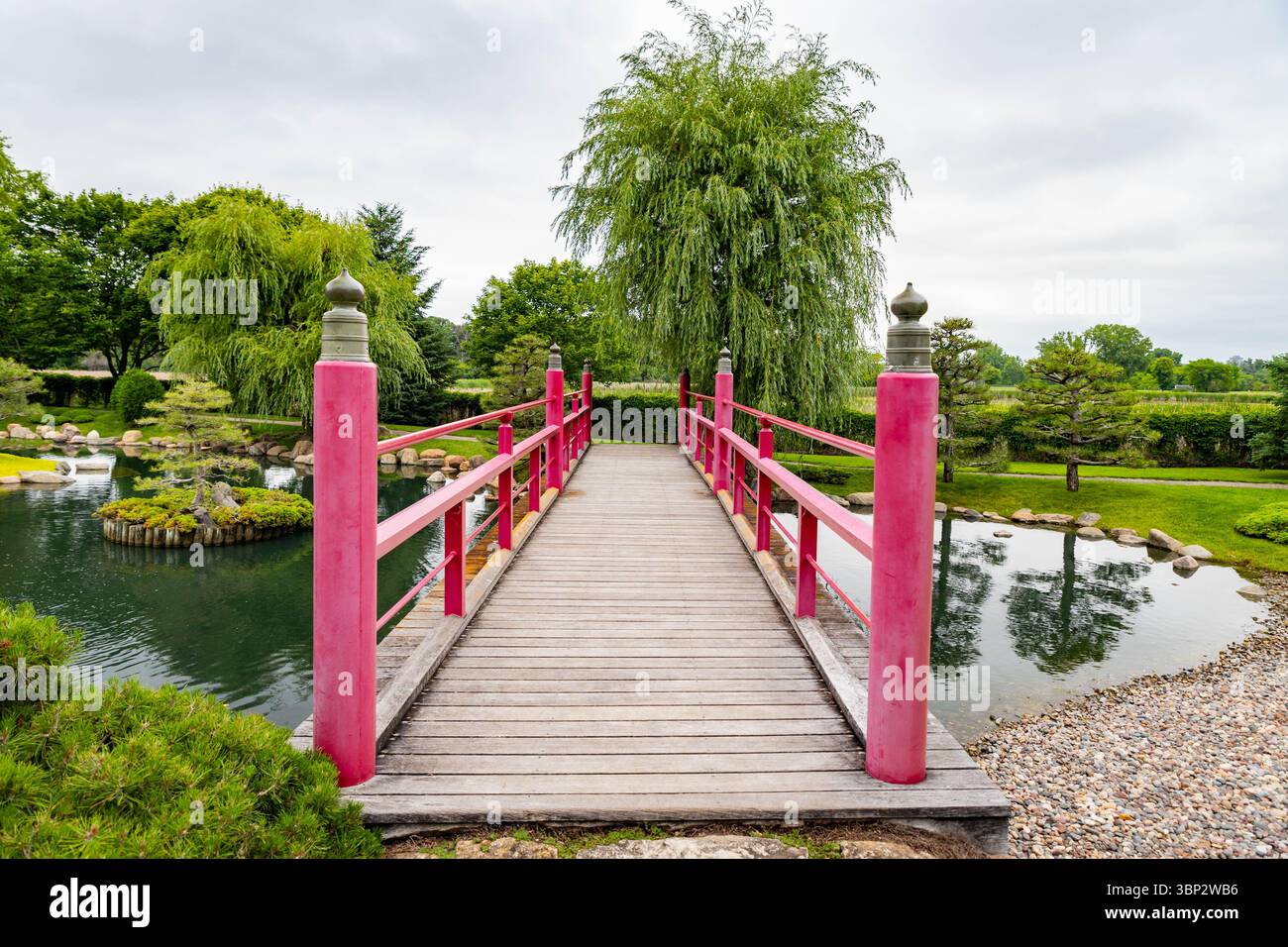 A beautiful traditional red bridge arches gracefully over water in the ...