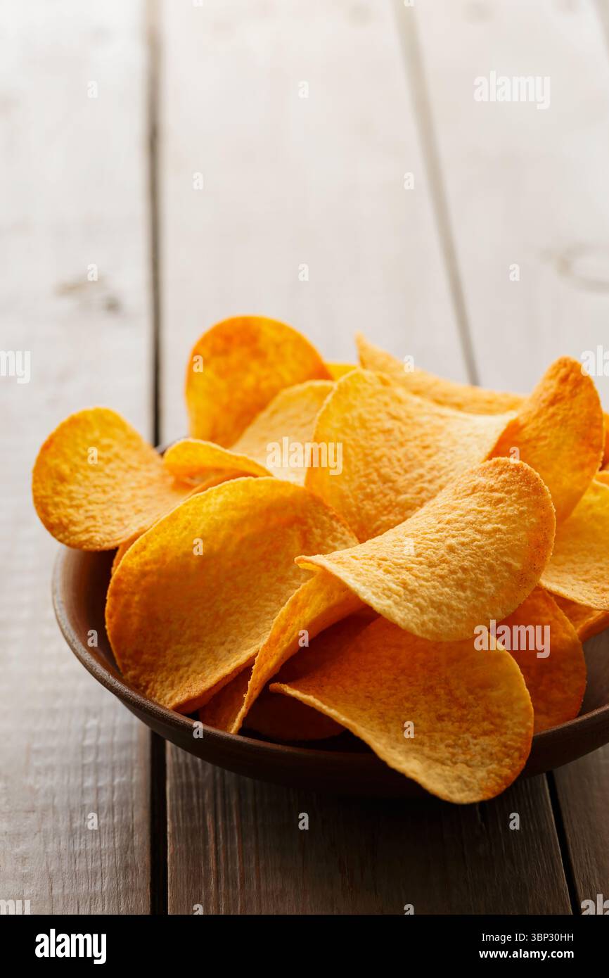 Crispy Potato Chips in Clay Bowl on Rustic Table Stock Photo
