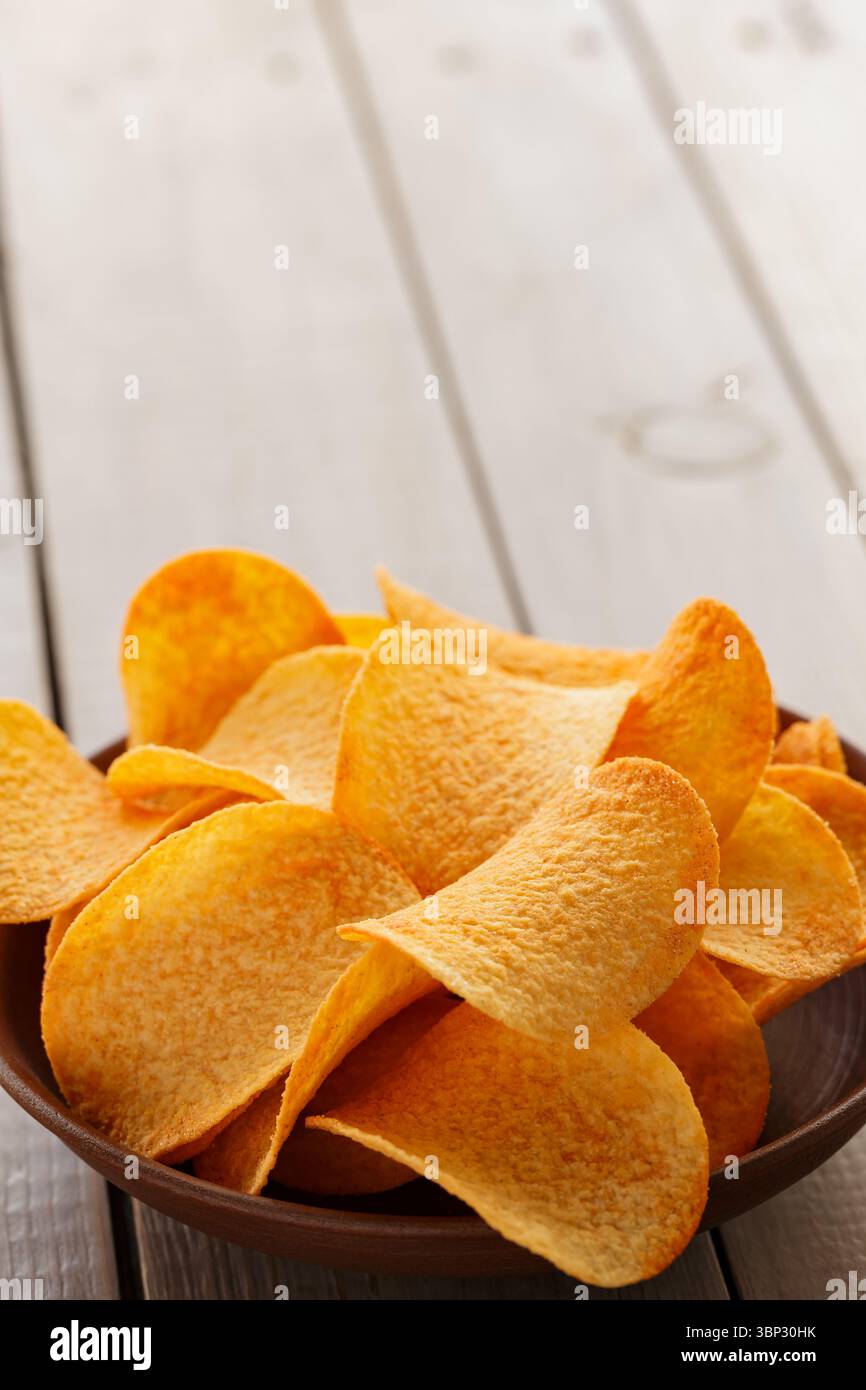 Crispy Potato Chips in Clay Bowl on Rustic Table Stock Photo