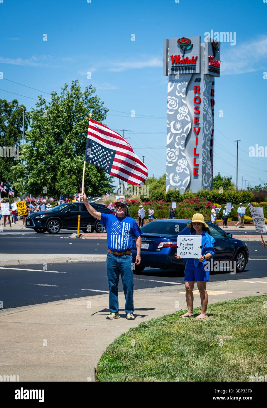 Two protesters hold an upside-down U.S. flag and sign that says 'Worst President Ever' at an Independence Day protest at the Westfield Galleria Stock Photo
