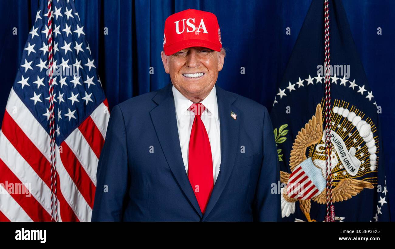 President Donald Trump stands in front of the U.S. flag and the presidential flag, wearing a red “USA” cap, dark suit, white shirt, and red tie. The pairing of national and executive symbols sets the tone for a formal Independence Day moment, highlighting themes of patriotism and authority. Washington, D.C. | July 4, 2025 | Image courtesy of the White House. Stock Photo