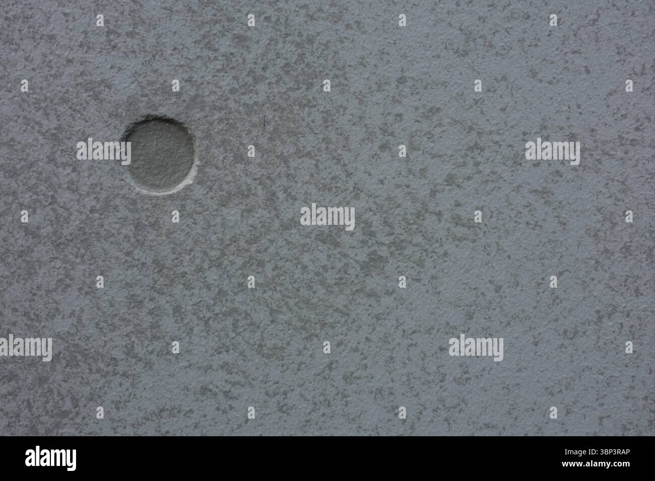Textured grey surface features single, round indentation on one side ...