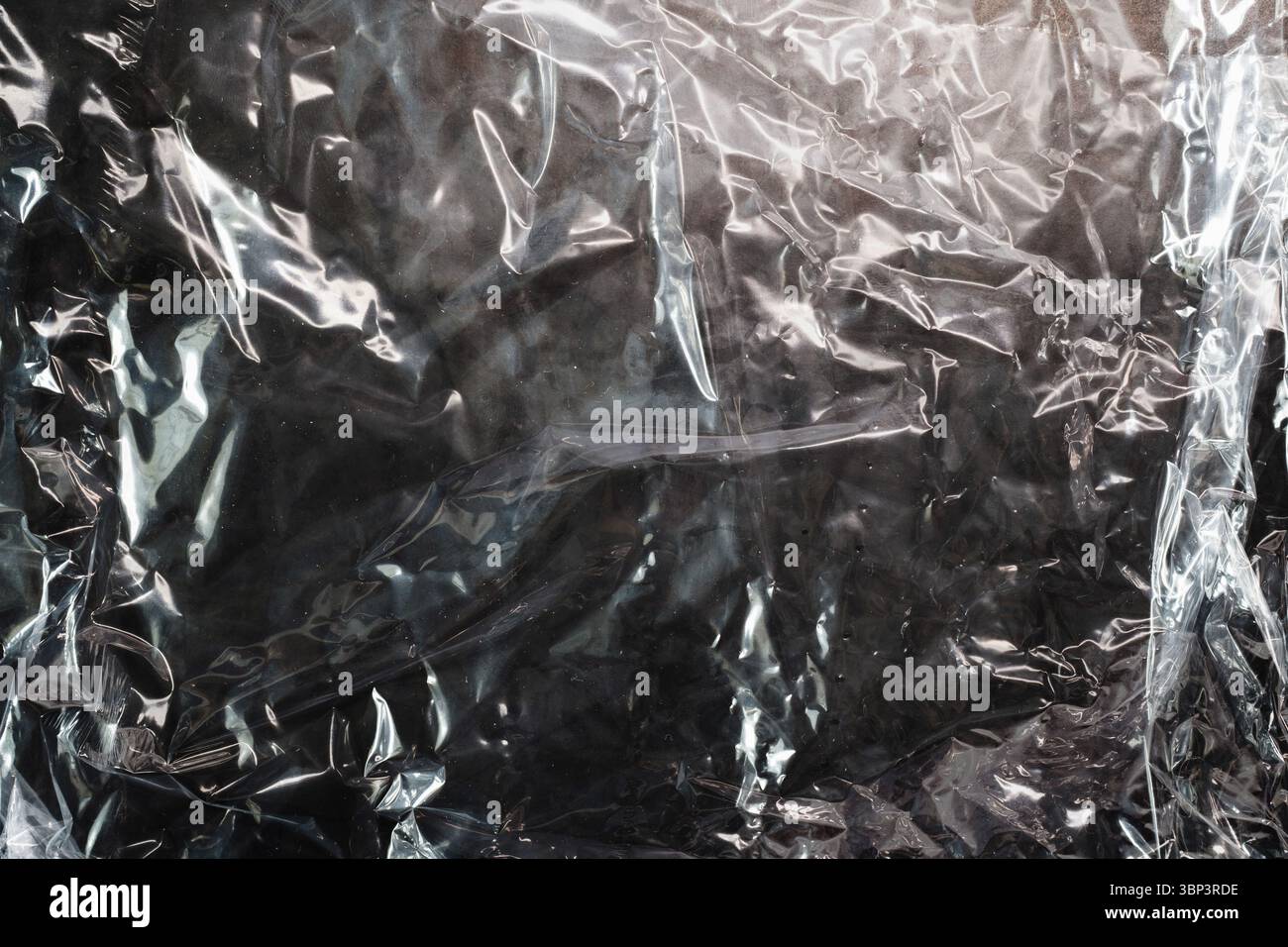 The texture of crumpled wrapping plastic against a dark background Stock Photo