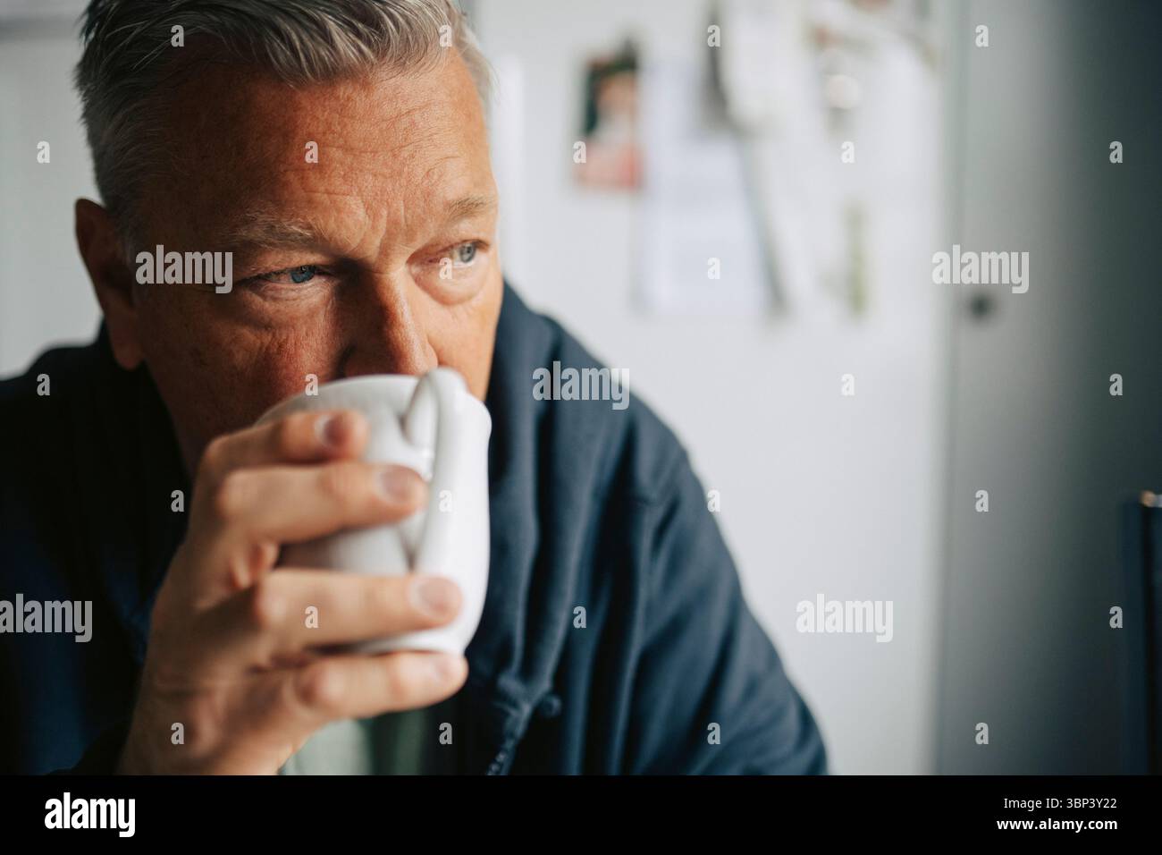 Thoughtful elderly man drinking coffee at home Stock Photo
