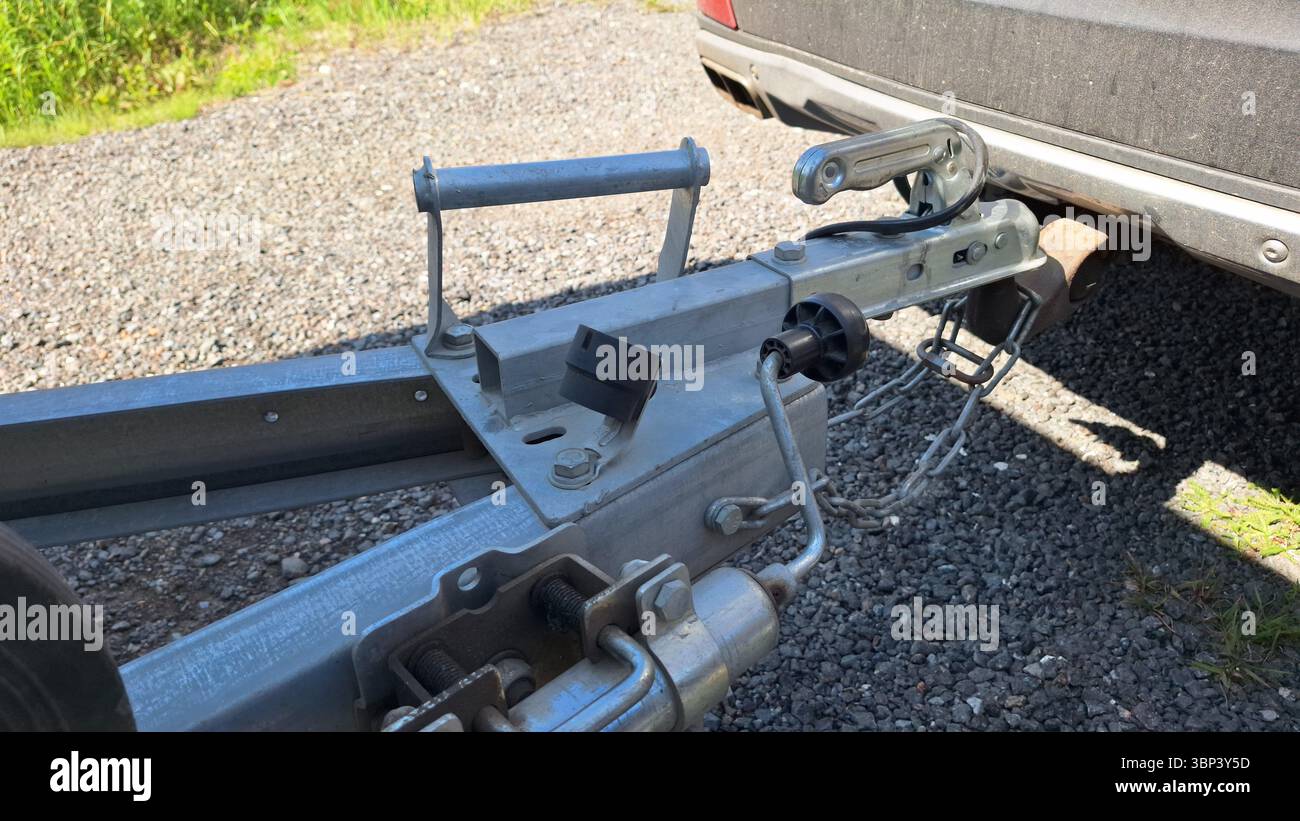 Close-up of metal trailer hitch attached to car on gravel surface Stock Photo