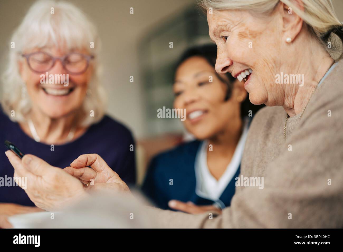 Happy senior woman using smart phone while spending leisure time in retirement home Stock Photo