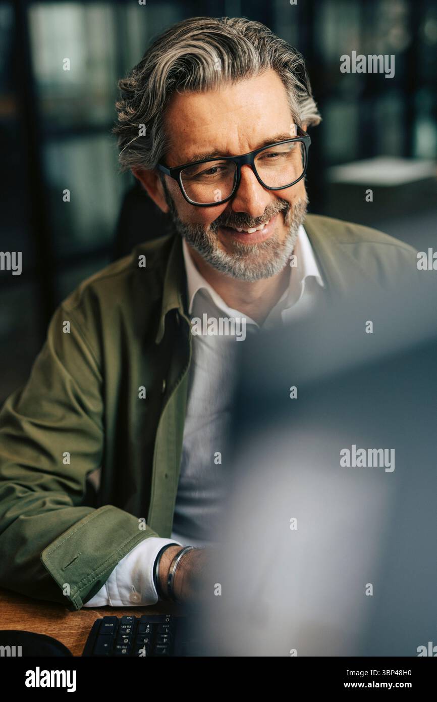 Smiling elderly businessman working on computer at office Stock Photo