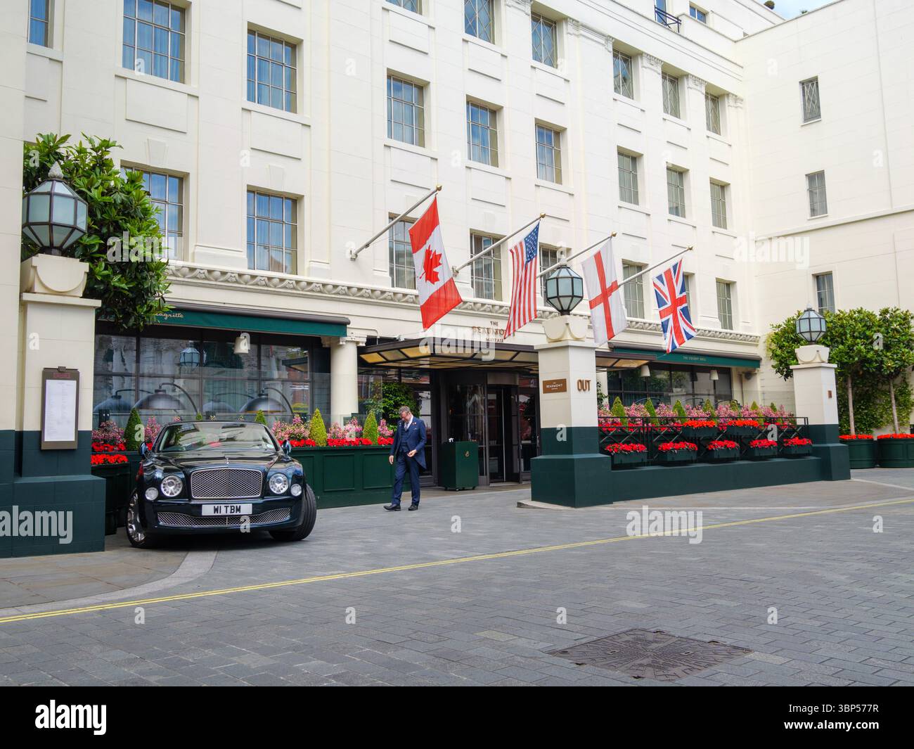 A concierge at The Beaumont Hotel in Mayfair, London, approaches a Bentley Mulsanne, illustrating the hotel’s dedication to premium service and its status as a luxury destination in one of the city’s most prestigious neighbourhoods Stock Photo