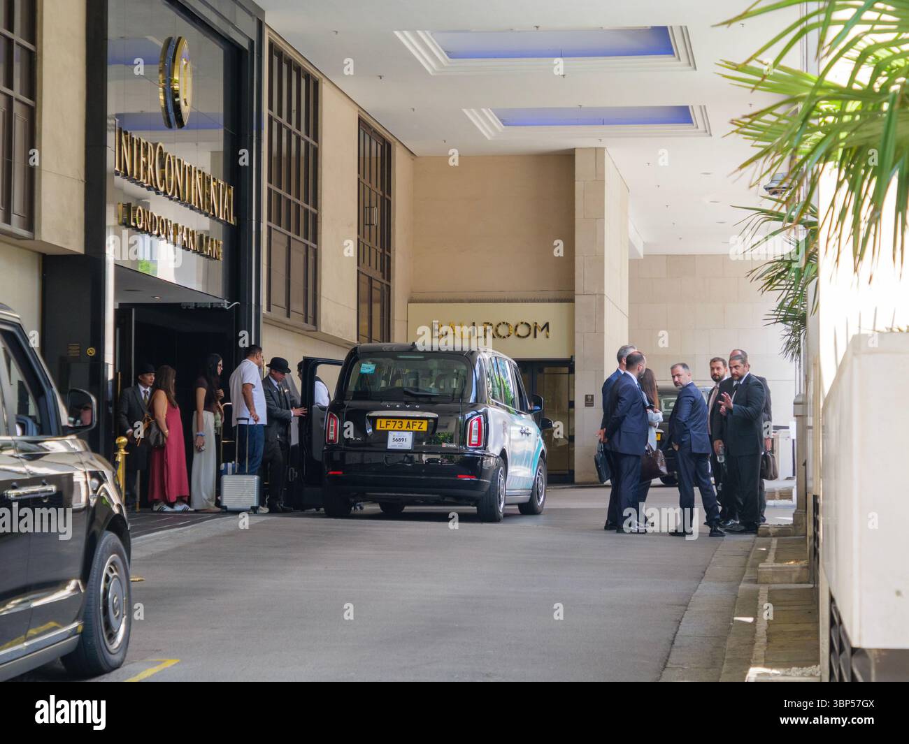 A concierge helps passengers board taxis outside the Intercontinental Hotel in Mayfair, London, as part of the city’s ongoing return to high-end tourism and business travel Stock Photo
