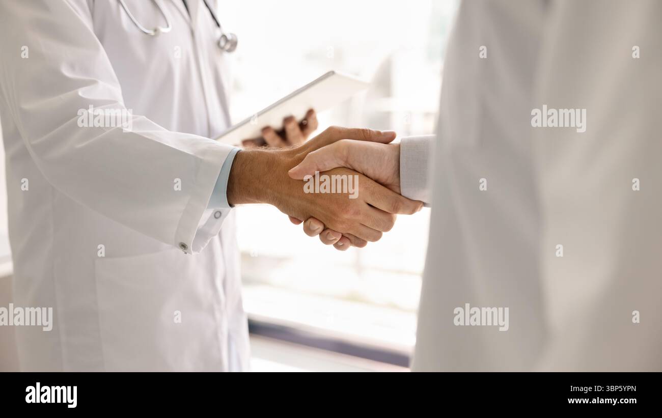 Two doctors in lab coats handshake close up Stock Photo