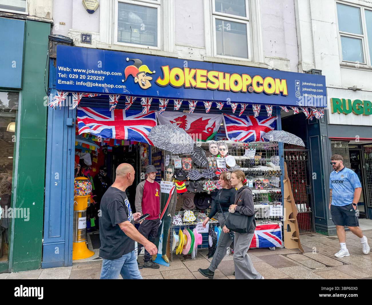 Oasis Tour Cardiff Concert Fans Wearing Band T-Shirts and Merchandise Outside Jokeshop - Smartphone Captured Stock Image