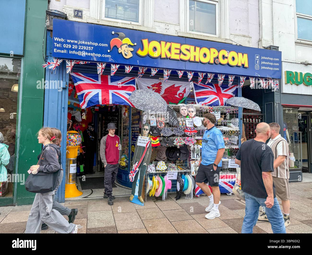 Oasis Tour Cardiff Concert Fans Wearing Band T-Shirts and Merchandise Outside Jokeshop - Smartphone Captured Stock Image