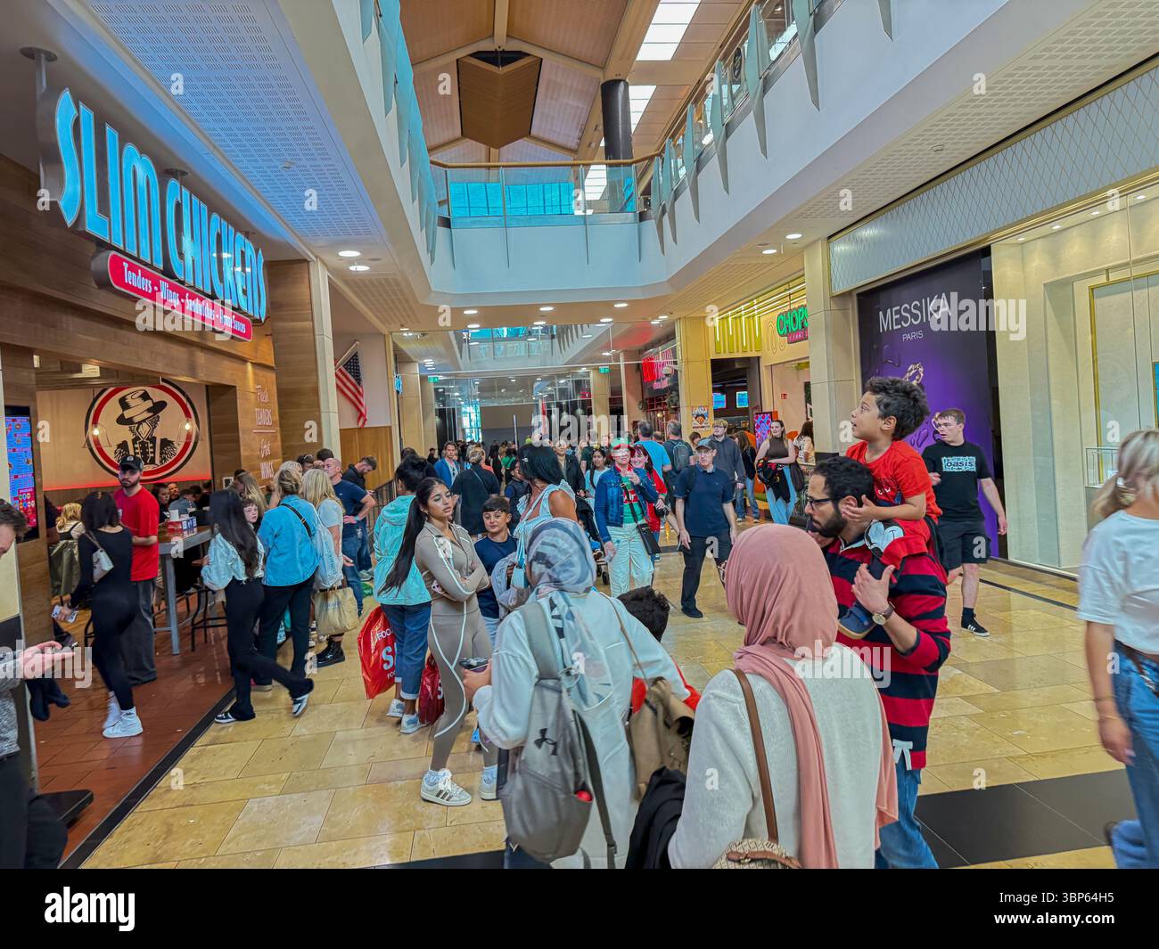Oasis reunion Live '25 Tour Cardiff Concert Fans Wearing Band T-Shirts and Merchandise in Stant Davids Shopping Mall - Smartphone Captured Stock Image