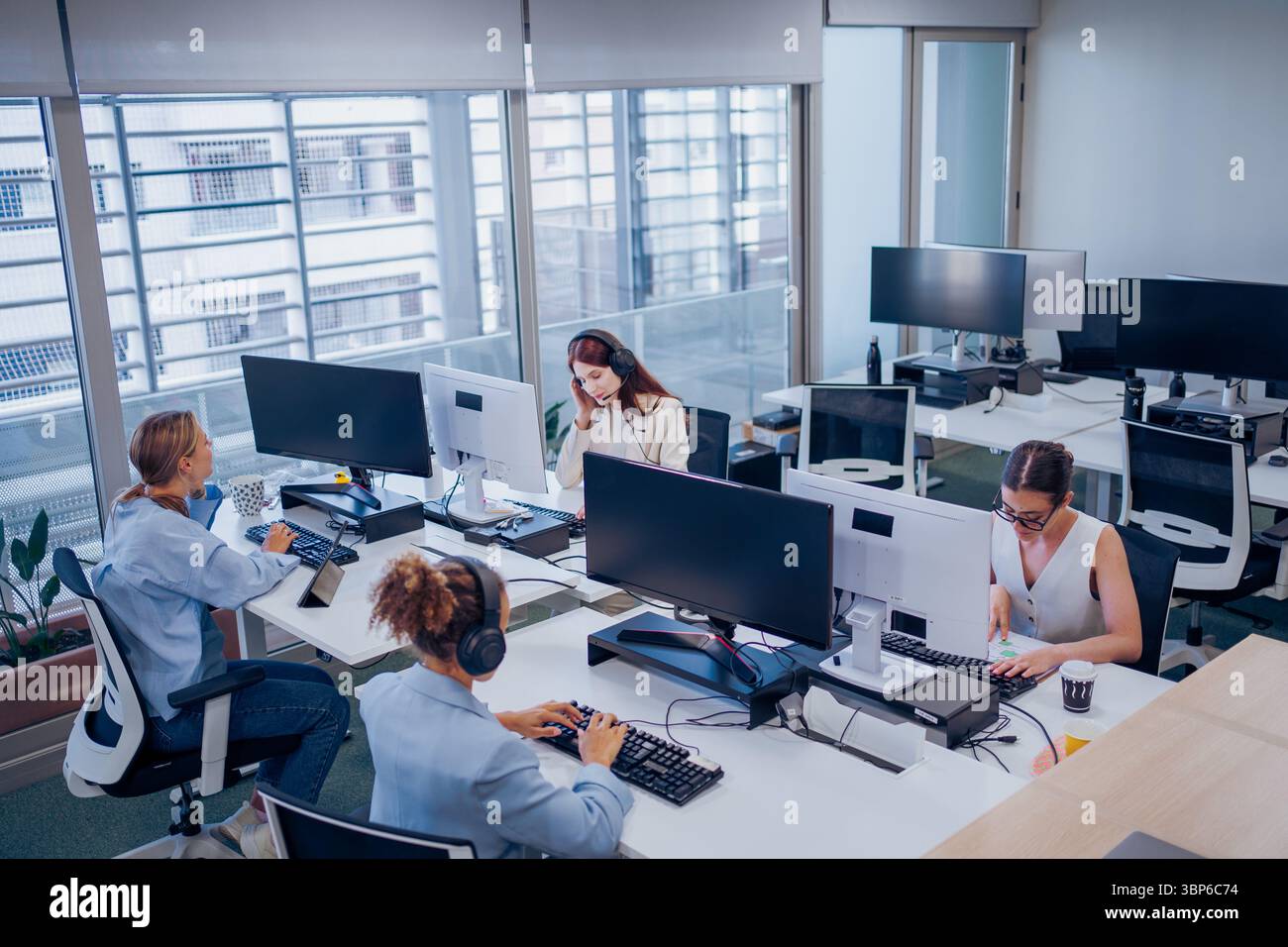 In a modern office, a diverse team collaborates effectively towards shared goals using technology Stock Photo