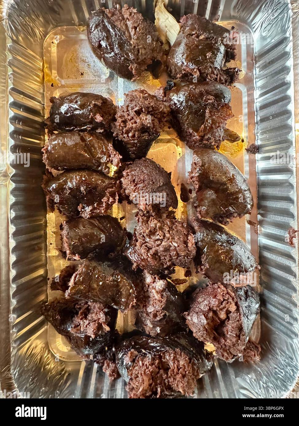 Cooked blood sausages sliced and served in a foil tray, traditional dish ready to be served. - Smartphone Captured Stock Image