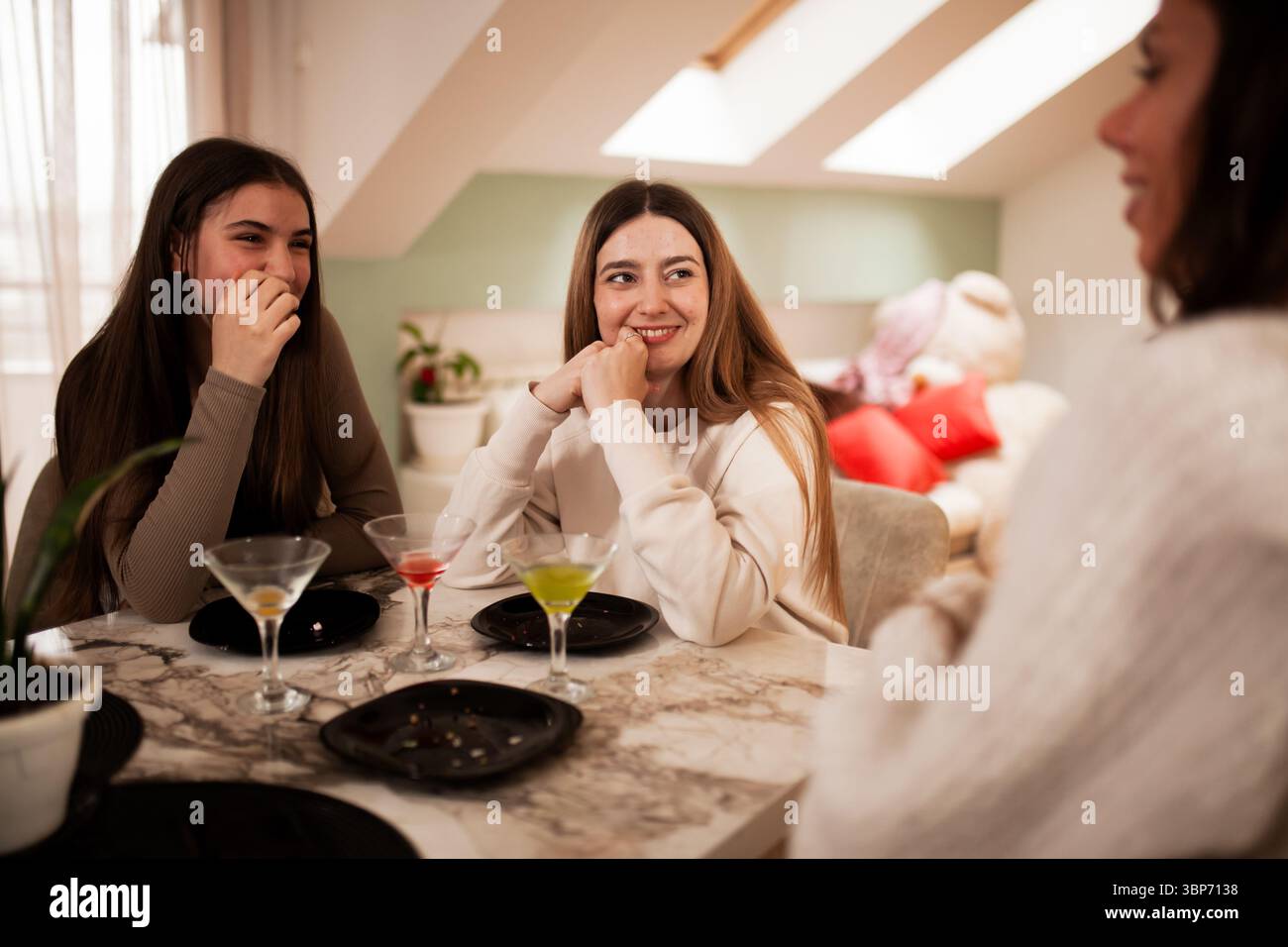 Three young women sharing laughter and conversation indoors while ...