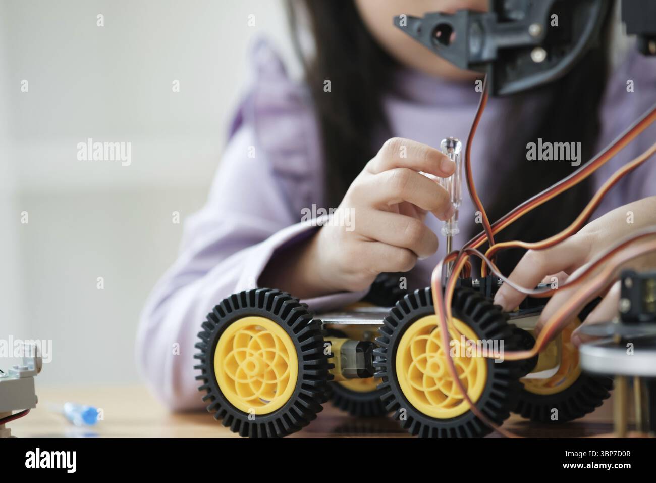 Asian girl concentrating on building a robot, embodying STEM education Stock Photo