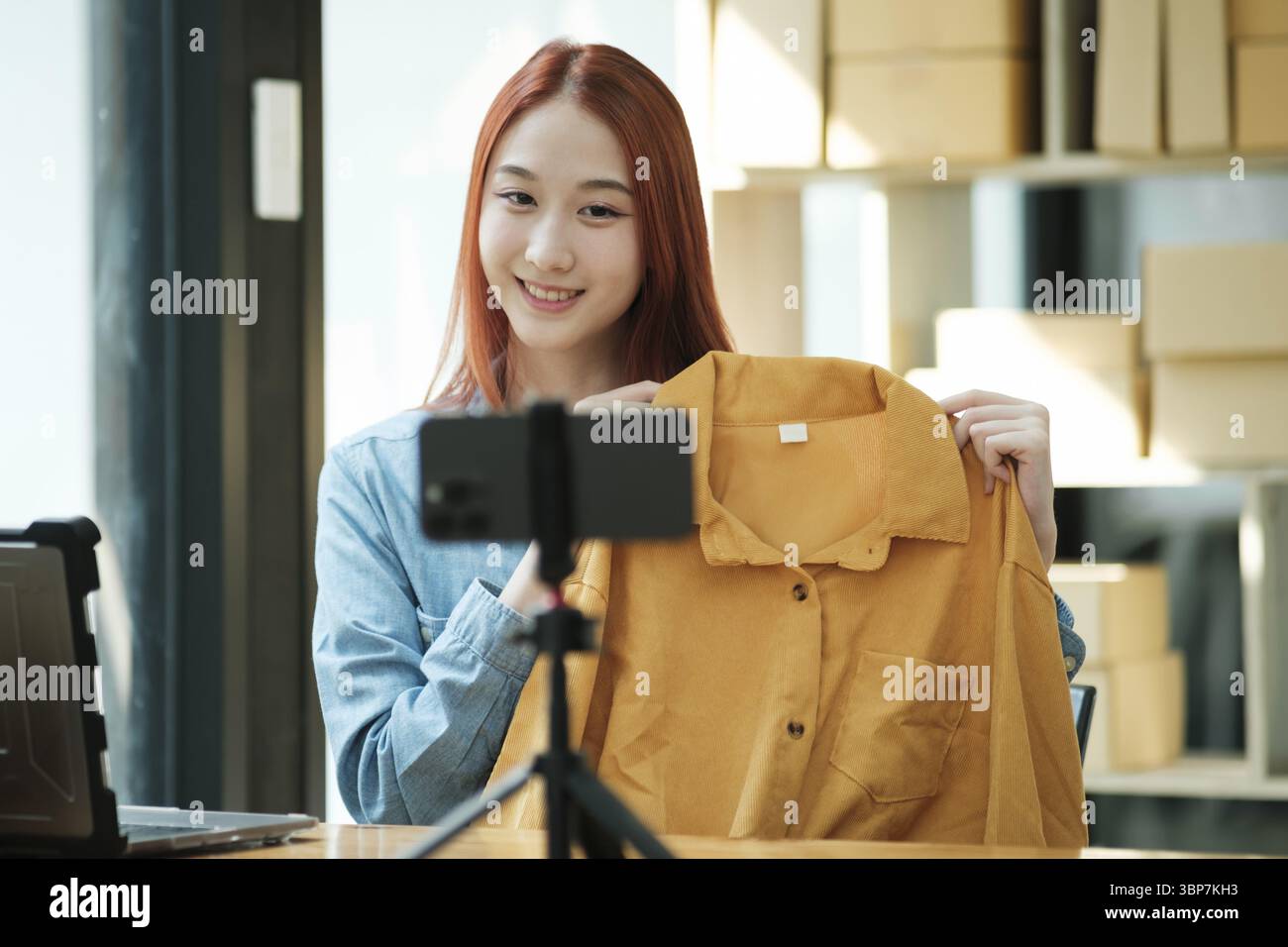 Woman with a social media influence is greeting the audience for recording vlog video live streaming, Lift the postage box during the live show to con Stock Photo