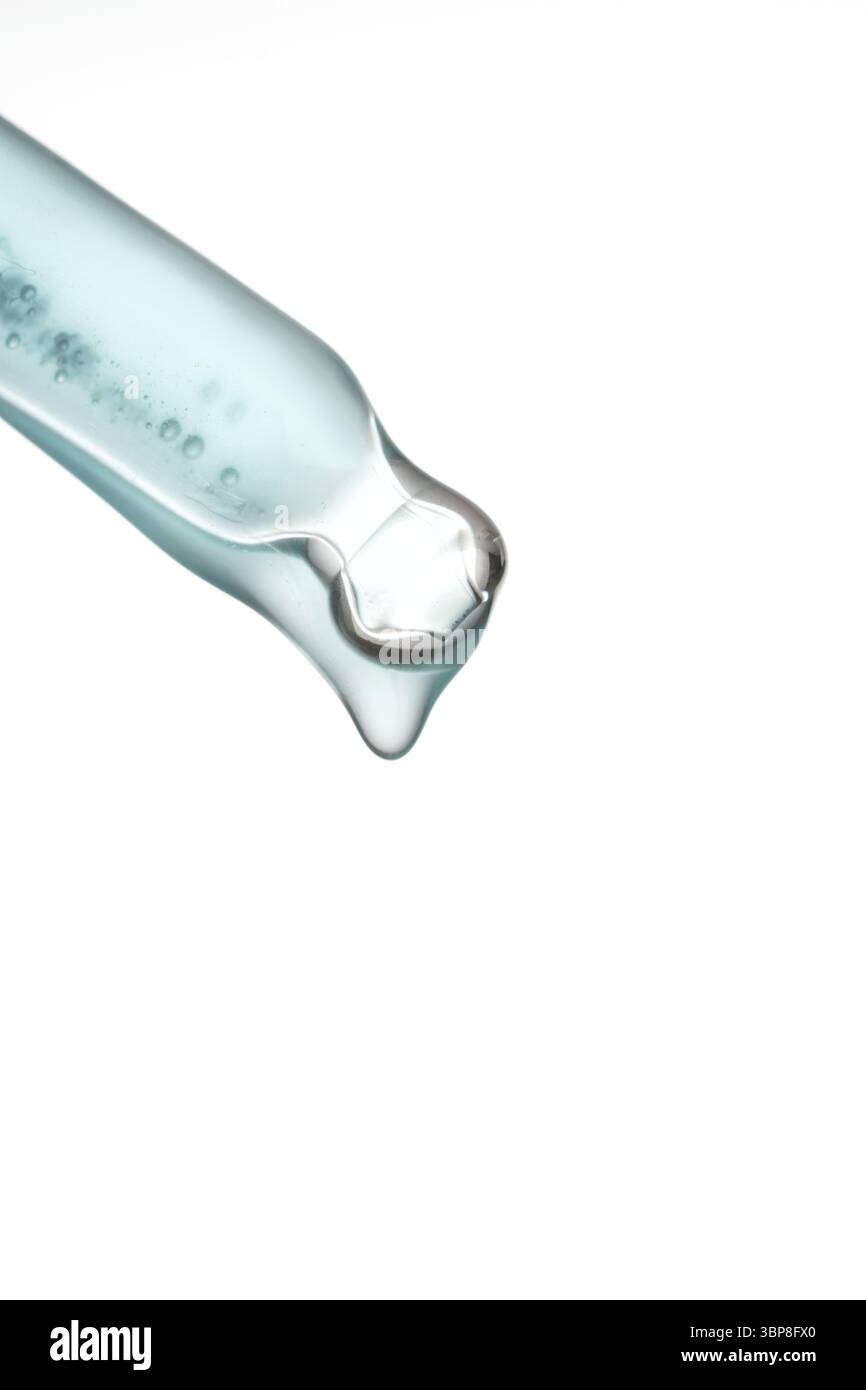 Tropfen eines Gesichtsserums mit Blasen, die aus einer transparenten Pipette auf weissem Hintergrund fliessen. Fluessiges Gel mit Kollagen in Grossauf Stock Photo