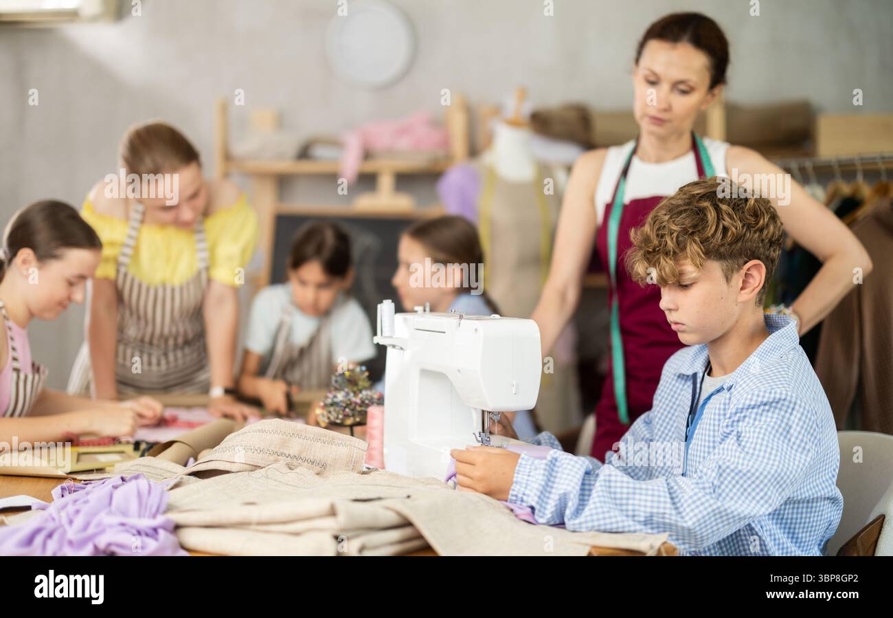 Engaged schoolboy stitching fabric on machine in sewing class Stock Photo