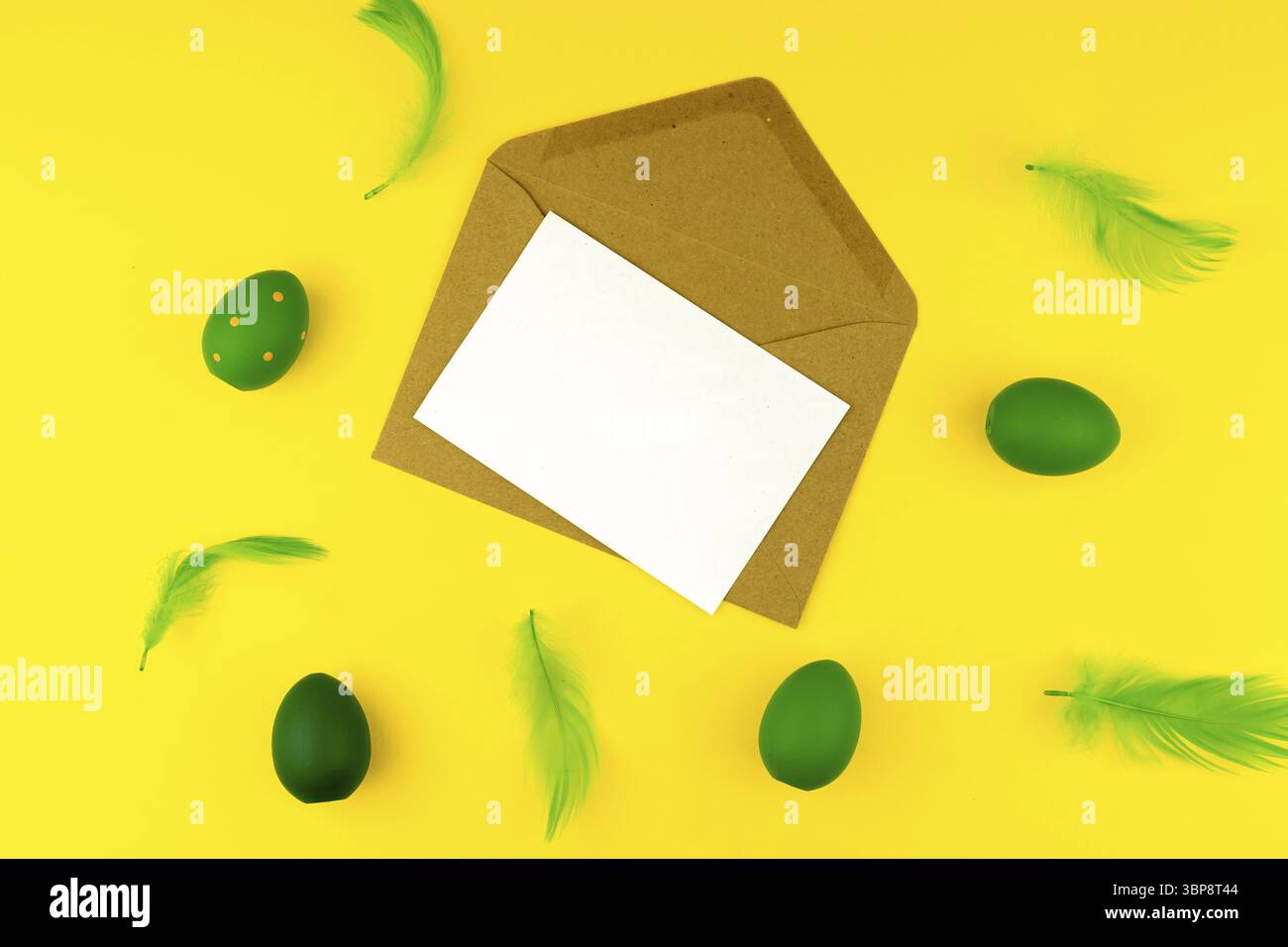 Spring Easter layout with green feathers and eggs, craft envelope and blank paper for text Stock Photo
