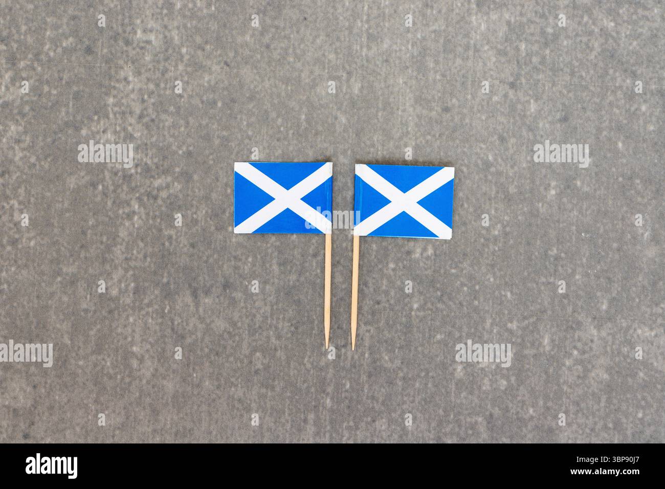 Two Vertical Scottish Flags Standing Side by Side on Grey Surface Stock Photo