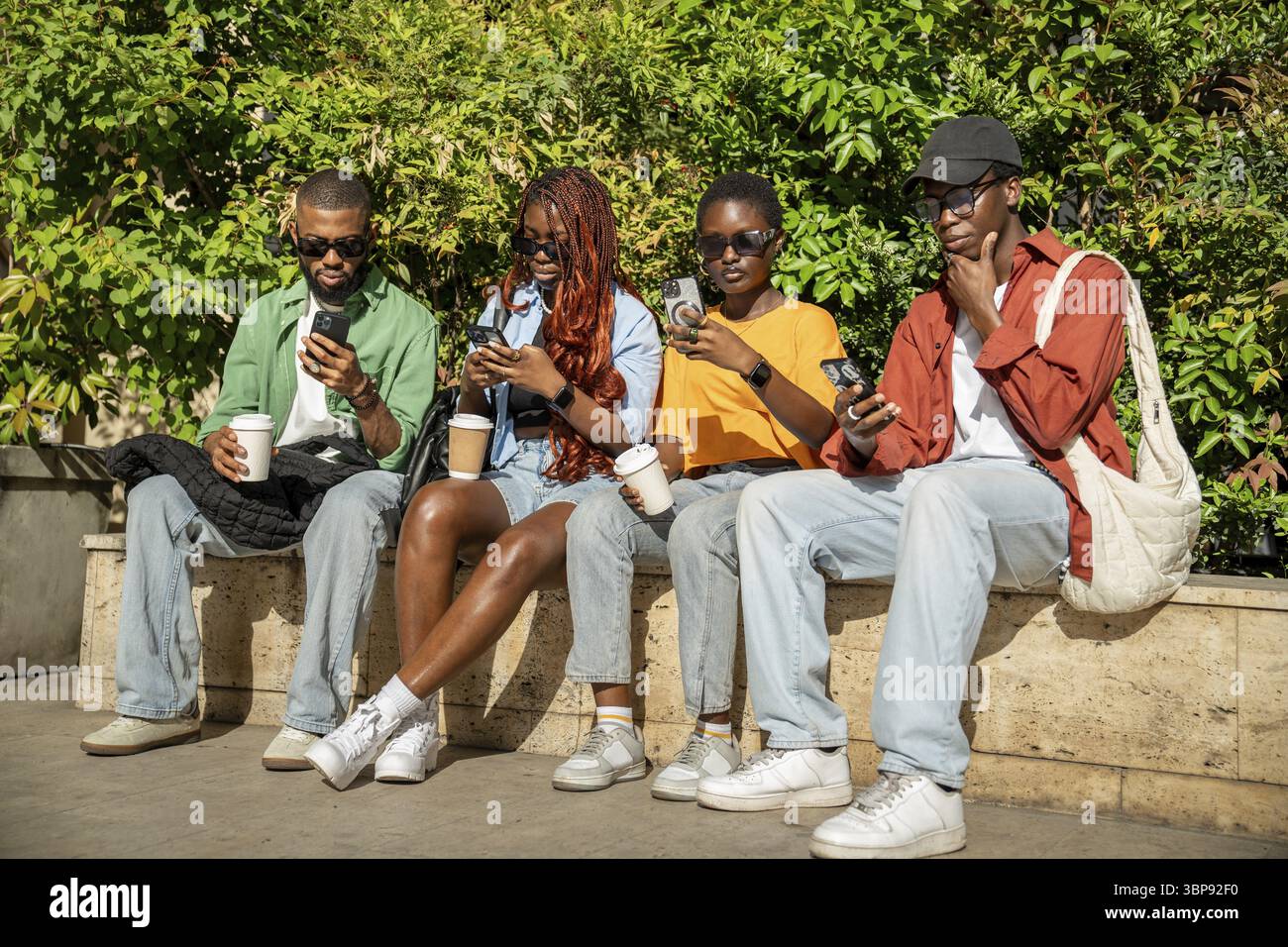 Interested dependent african american friends addicted to phones ignore each other at joint meeting use smartphones, typing messaging, devoting time t Stock Photo